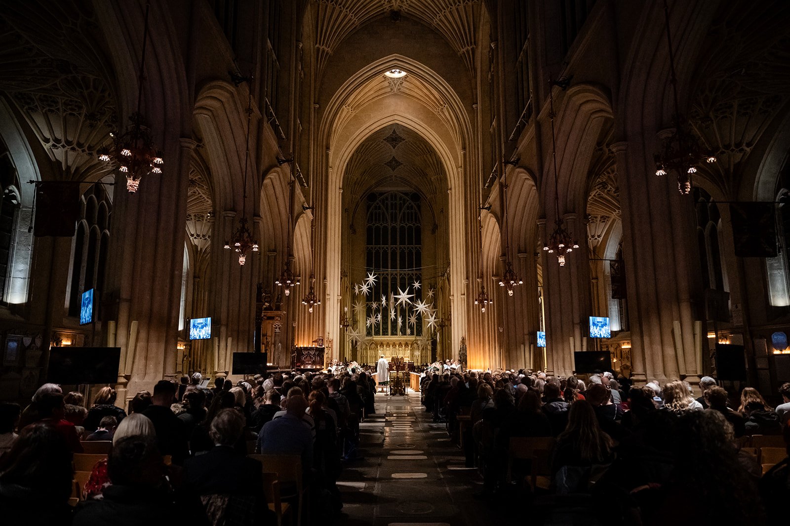 A dark church with a full congregation, watching the choir sing